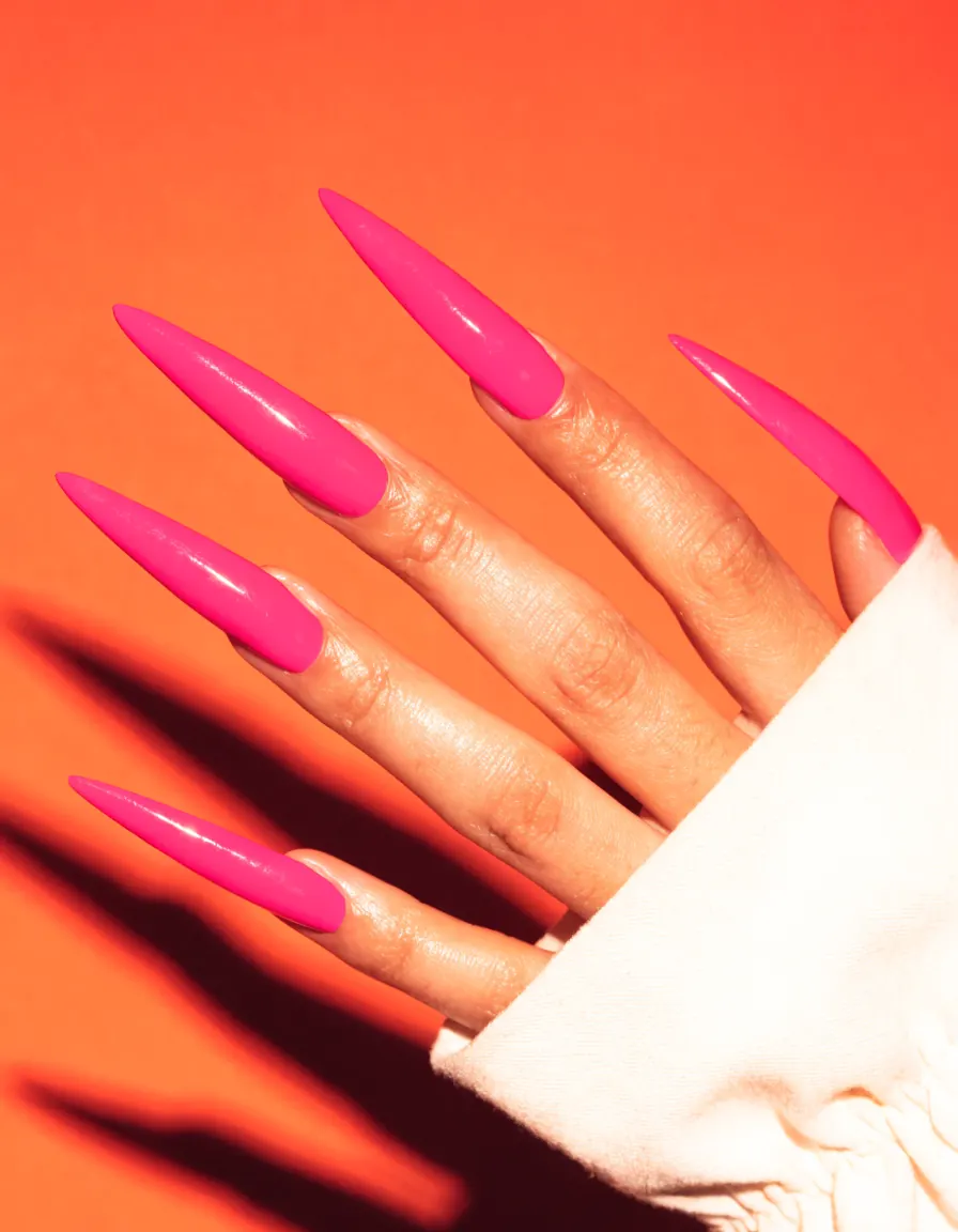 Hand with long hot pink stiletto acrylic nails